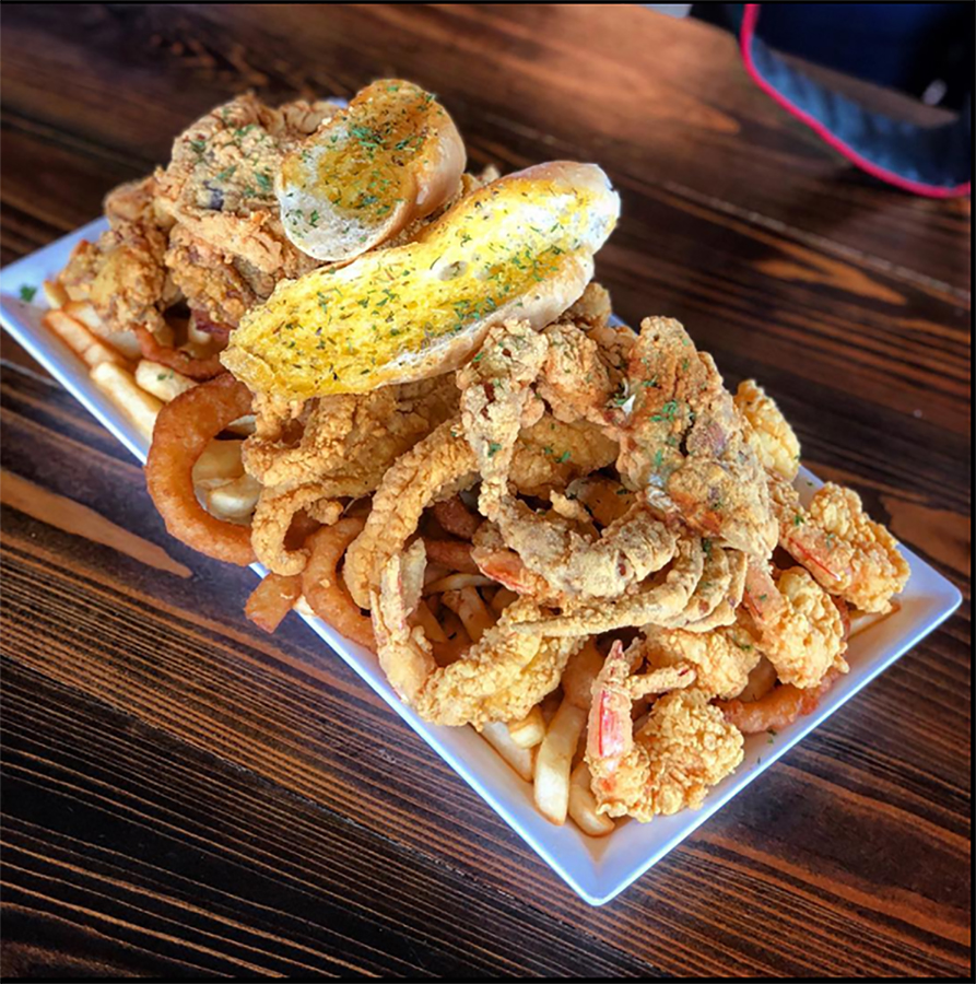 a plate of fried seafood resting on onion rings and French fries - bulk spices