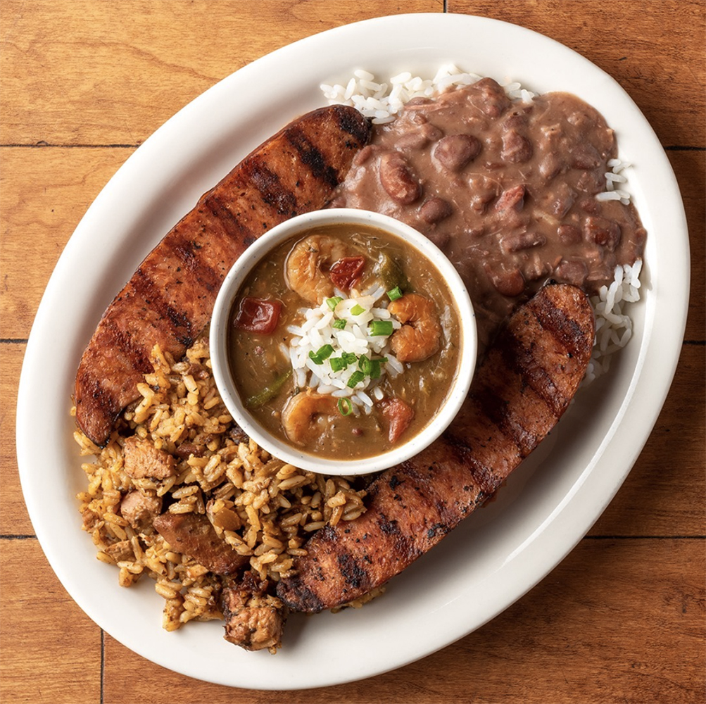 A large plate with white rice and beans, fried rice with sausage, and a bowl of gumbo -bulk spices